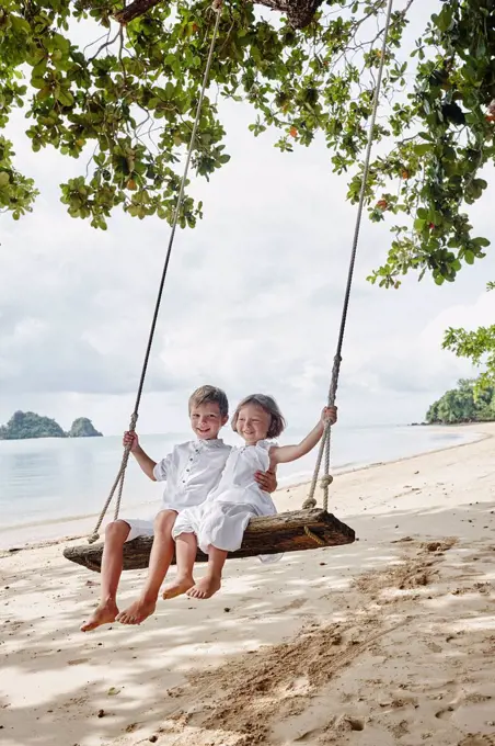 Thailand, Ko Yao Noi, happy boy and little girl on a swing on the beach