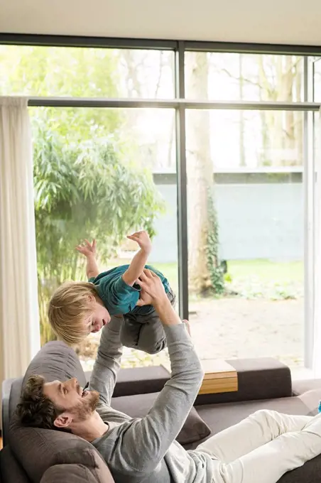 Happy father playing with son on sofa at home