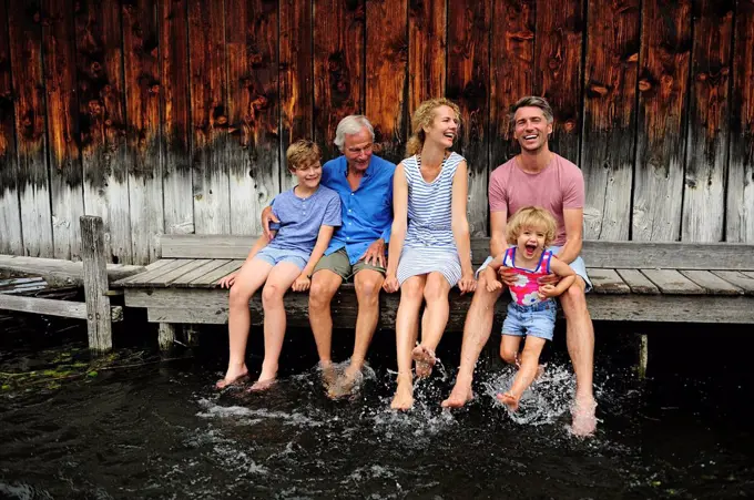 Family sitting together on jetty splashing with water