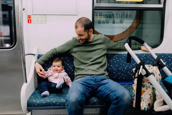 South Korea, Busan, father and baby girl traveling by subway with a stroller