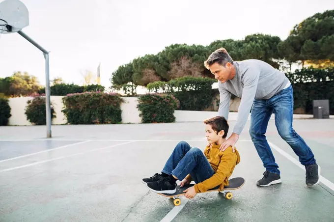 Father assisting son riding skateboard