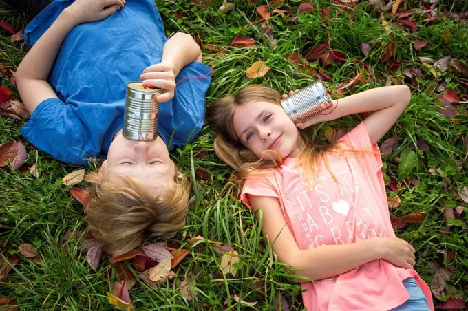 Boy and girl on a meadow having fun with tin can phone