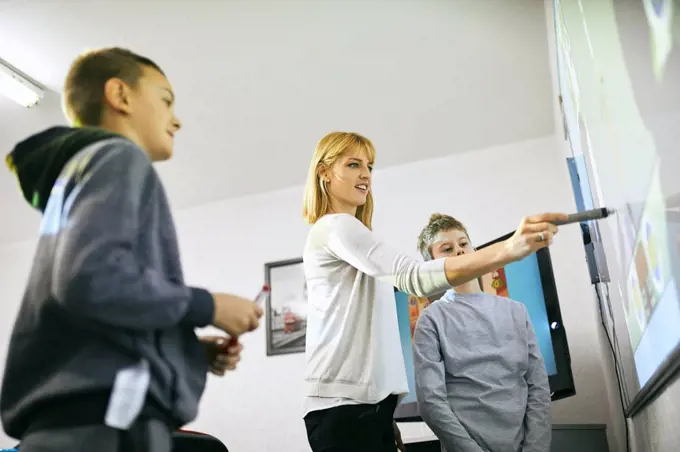 Teacher with students in class at interactive whiteboard