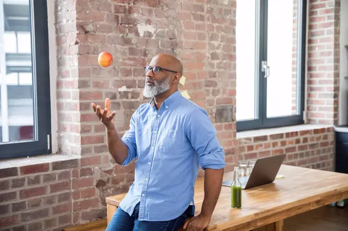 Freelancer throwing apple in the air in a loft