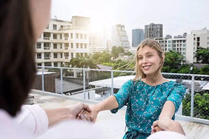 Young woman holding hands with boyfriend on rooftop