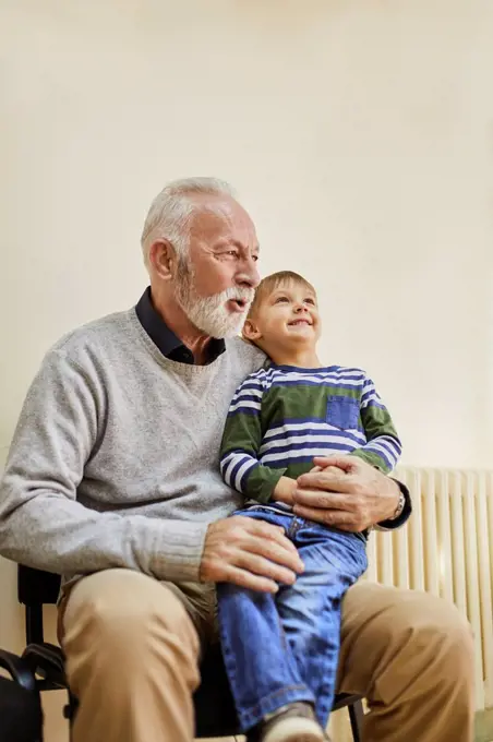 Boy sitting on grandfather's lap in waiting room