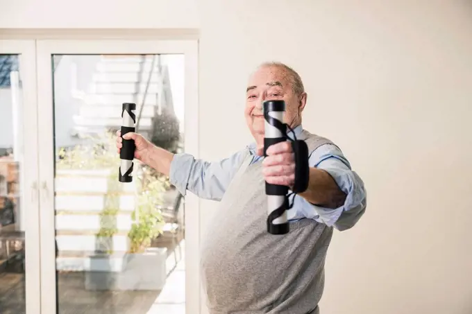 Portrait of smiling senior man doing an arm exercise