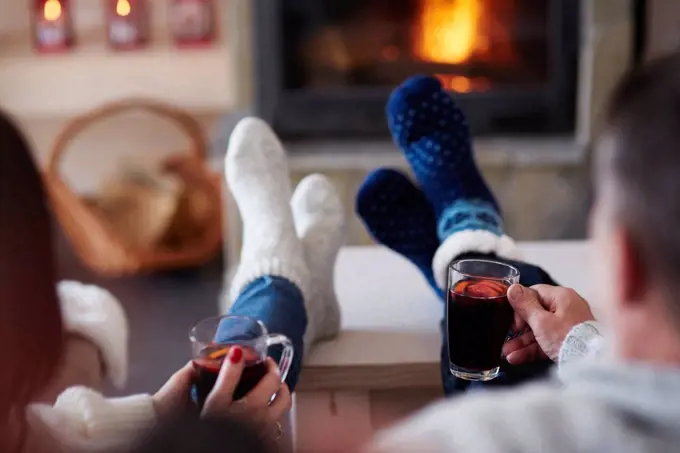 Mature couple with hot drinks in living room at the fireplace