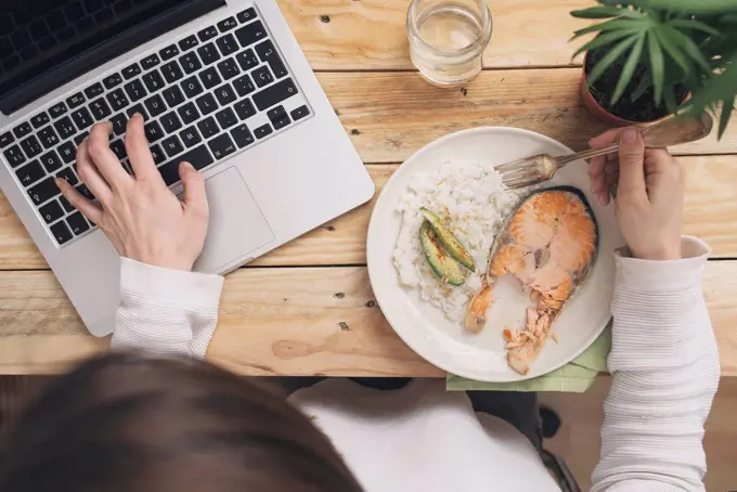 Woman having lunch and using laptop