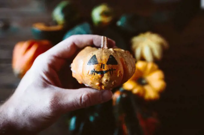 Man's hand holding painted Jack O'Lantern