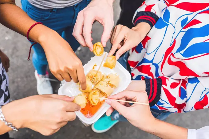 Thailand, Bangkok, Khao San Road, group of friends tasting local food on street market, close-up