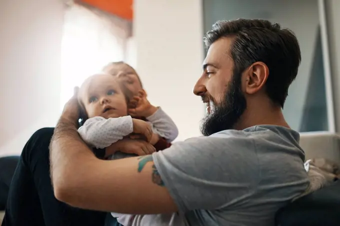 Happy father with baby girl and little son together at home