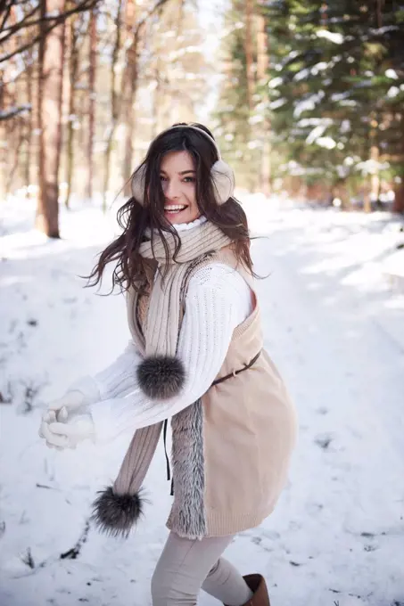 Portrait of laughing young woman having snowball fight in forest