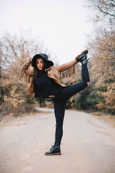 Portrait of young woman standing on one leg outdoors