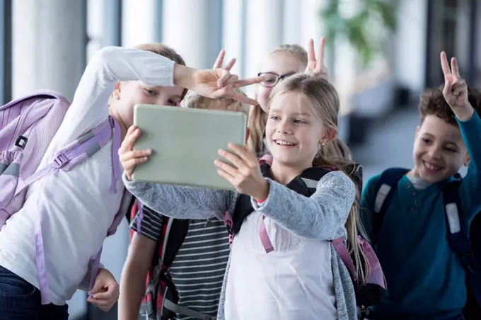 Happy pupils taking a selfie with tablet in school