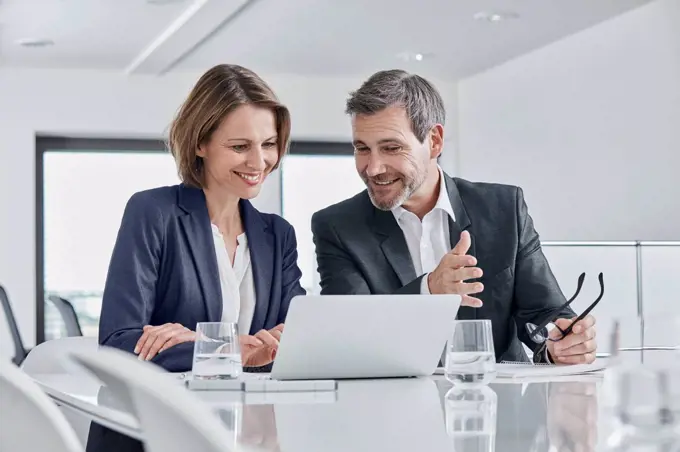 Businessman and businesswoman having a meeting in office with laptop