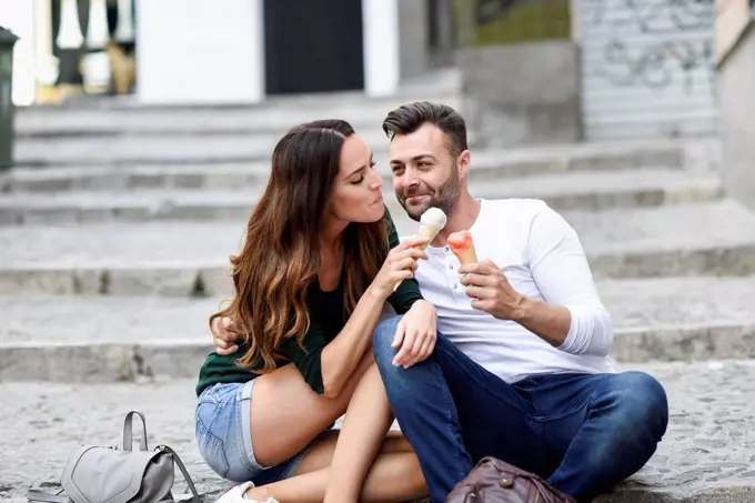 Tourist couple sharing ice cream cones in the city