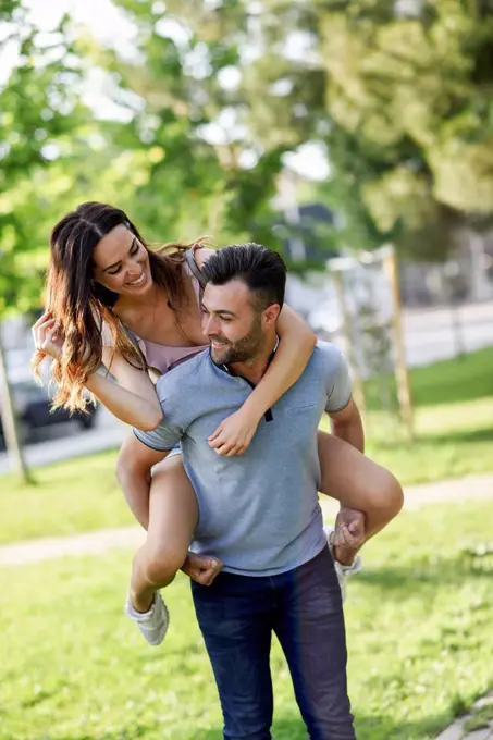 Happy man giving girlfriend a piggyback ride in park