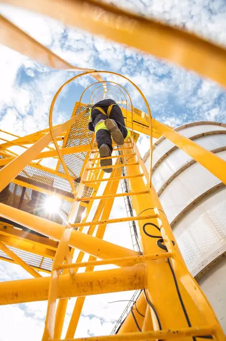 Worker climbing up ladder at tank