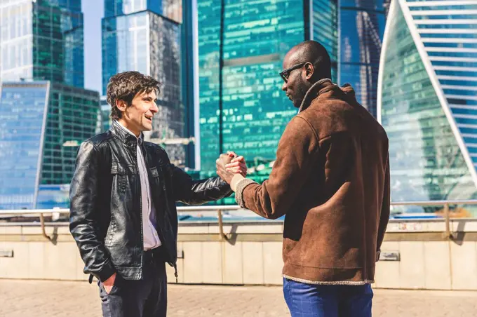 Russia, Moscow, two businessmen in front of modern office buildings