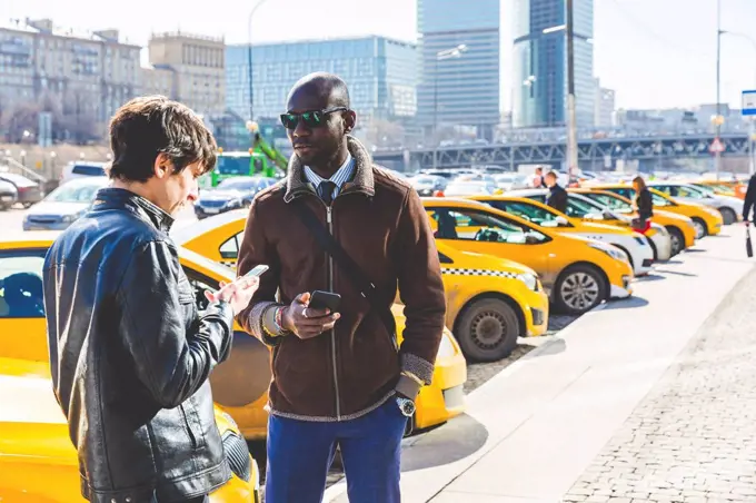 Russia, Moscow, two businessmen with smartphones in the city