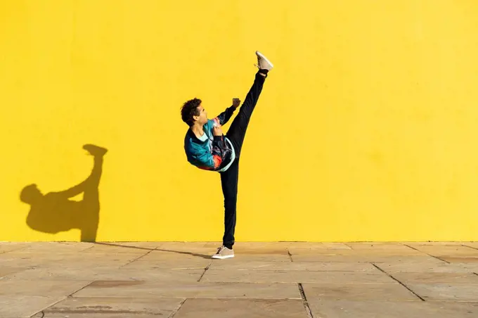 Acrobat doing movement training in front of a yellow wall