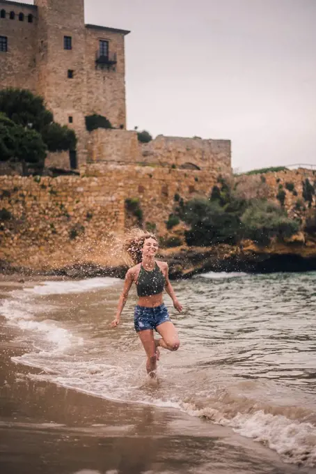 Happy young woman running on the beach