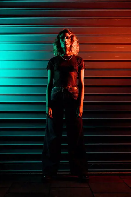 Stylish young woman at night in front of roller shutter