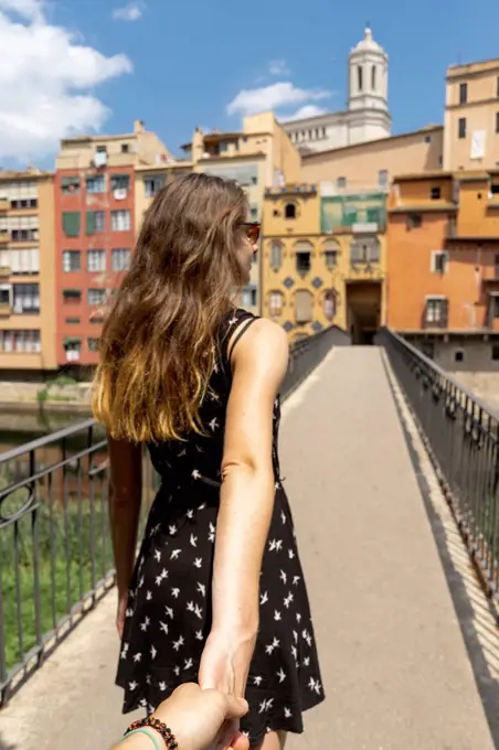 Spain, Girona, woman holding man's hand walking in the city