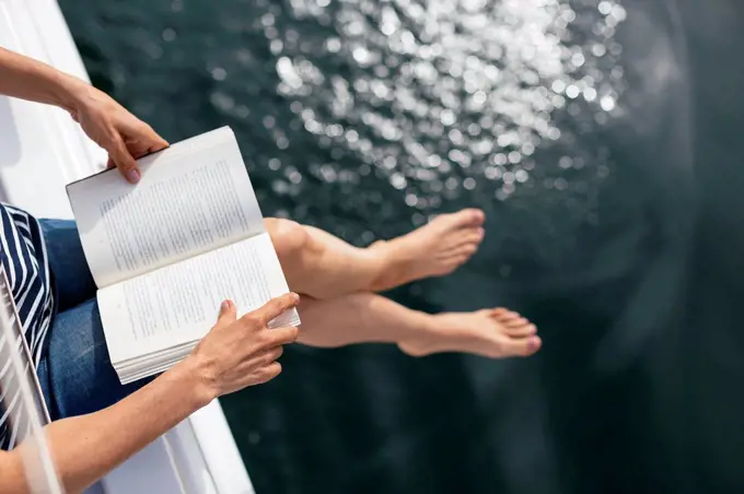 Woman sitting on sailing boat, reading a book