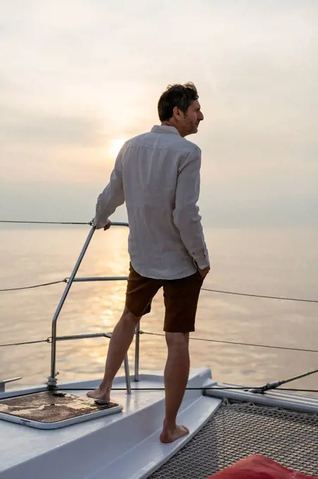 Marure man on catamaran, looking ta view