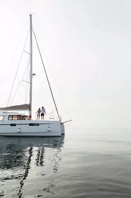 Couple setting off for a sailing trip on a catamaran