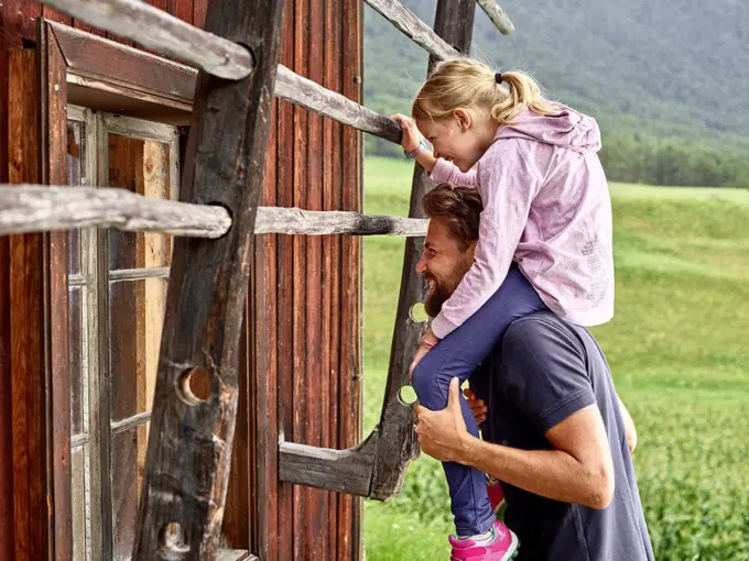 Happy father and daughter at wooden hut in the countryside