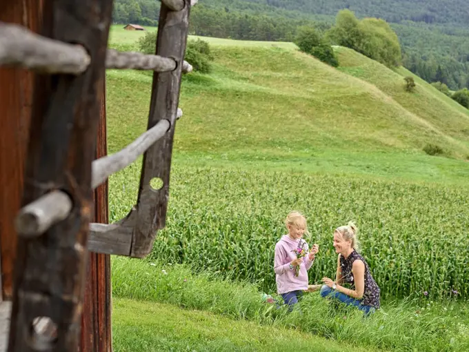 Happy mother and daughter picking flowers in the countryside