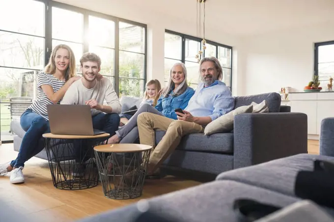 Extended family sitting on couch, using mobile devices