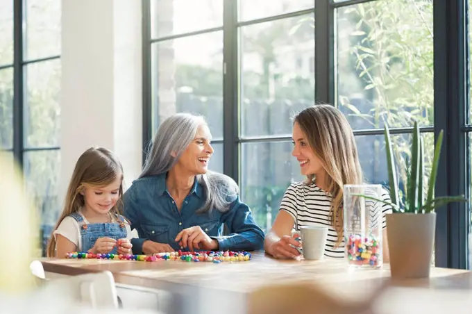 Grandmother and granddaughter and mother threading beads