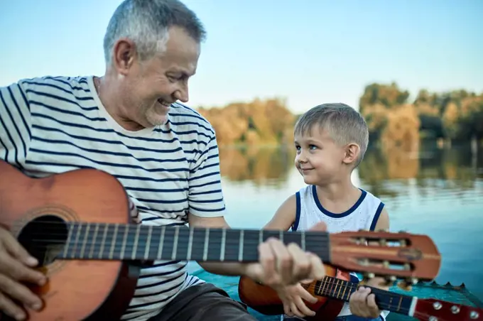 Grandfather teaching grandson playing guitar