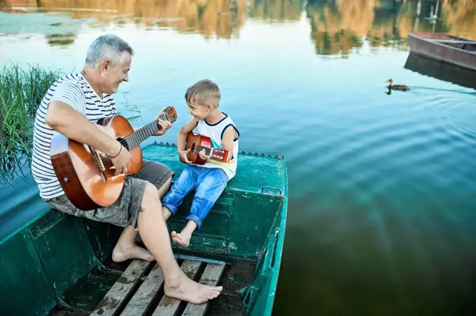 Grandfather teaching grandson playing guitar