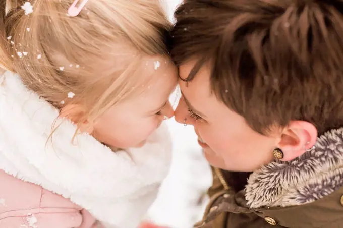 Little girl snuggling with her mother in the snow