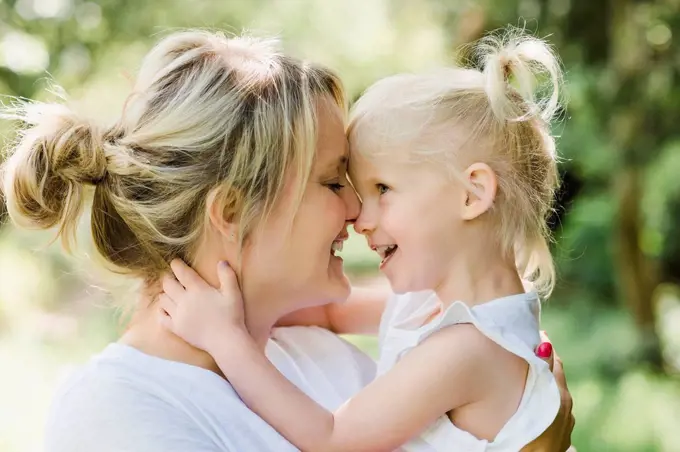 Happy mother cuddling her daughter in nature