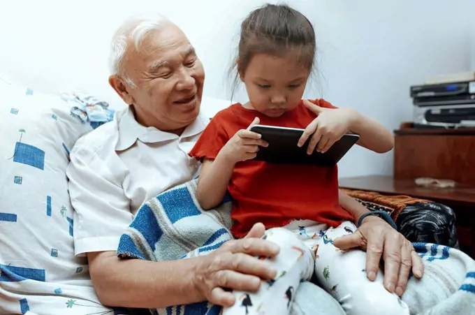 Grandfather and granddaughter with digital tablet at home