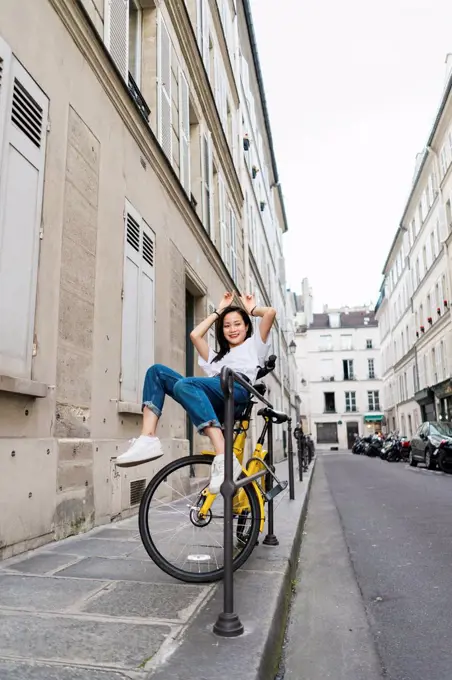 Playful young woman on bicycle at the roadside