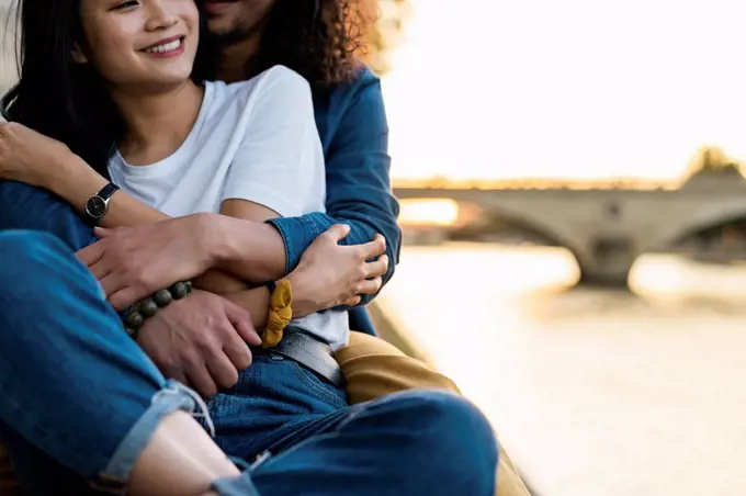 France, Paris, happy young couple hugging at river Seine at sunset