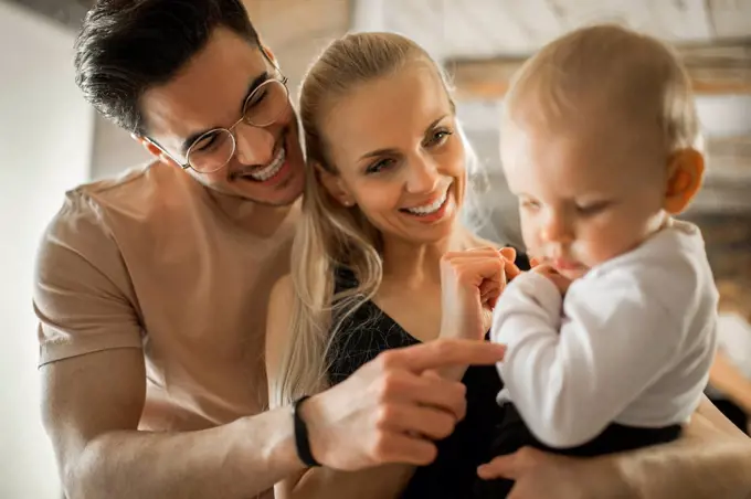 Happy young parents spending time at home with their baby girl