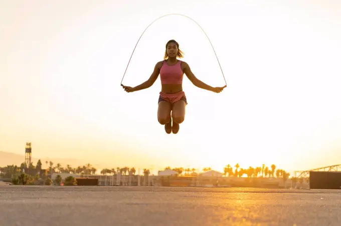 Spain, Barcelona, young black woman skipping rope at sunrise