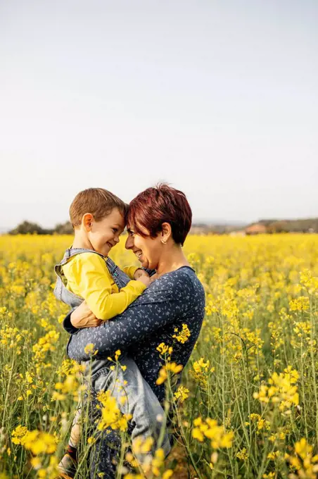 Mother standing with her little son in a rape field