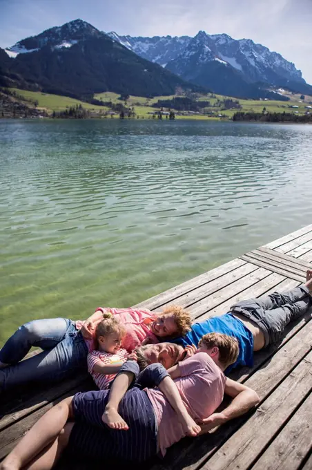 Austria, Tyrol, Walchsee, family lying on a jetty at the lakeside