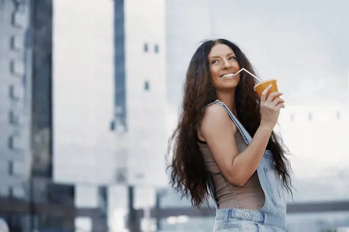 Woman standing in the city, drinking coffee