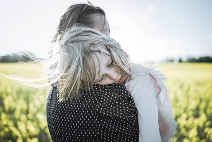 Portrait of little girl on her mother's arms in rape field