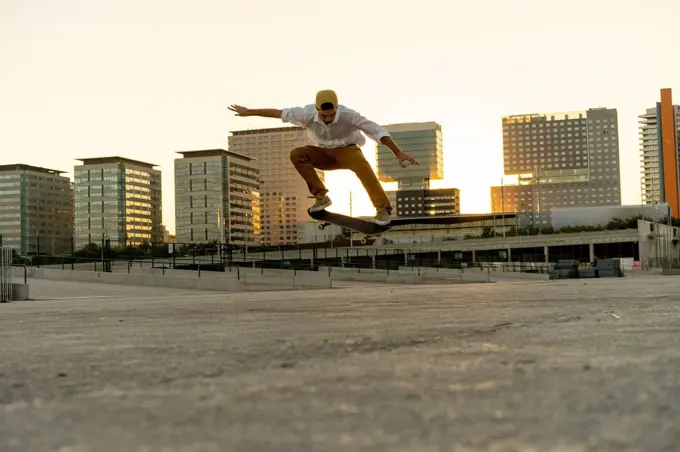 Young man doing a skateboard trick in the city at sunset